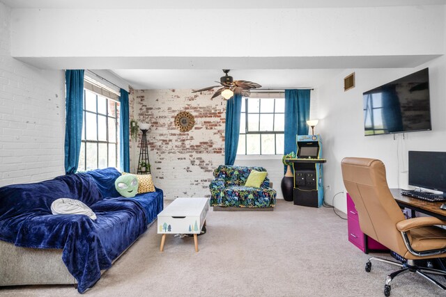 living area featuring carpet flooring, brick wall, visible vents, and plenty of natural light