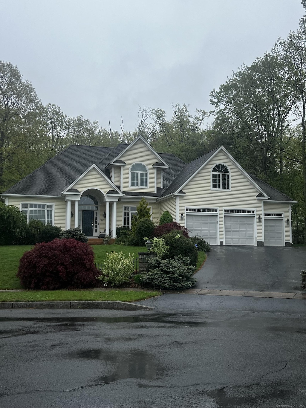 traditional-style house with a shingled roof, an attached garage, a front yard, and aphalt driveway