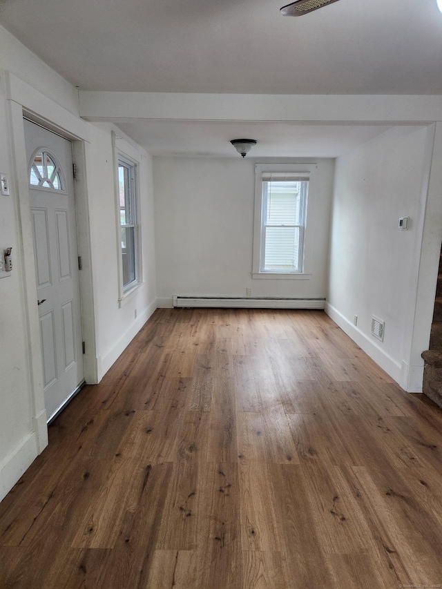 foyer entrance featuring a baseboard radiator, a healthy amount of sunlight, and wood finished floors