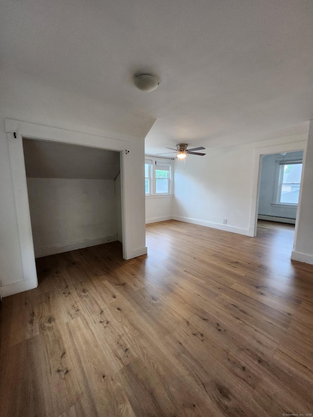 interior space featuring a ceiling fan, baseboards, wood finished floors, and baseboard heating