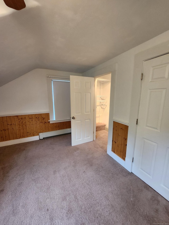 bonus room with carpet flooring, ceiling fan, a baseboard heating unit, wooden walls, and lofted ceiling