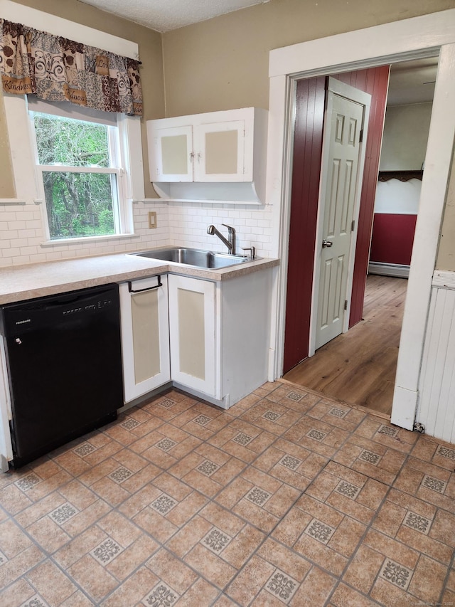 kitchen with a sink, white cabinetry, black dishwasher, and backsplash