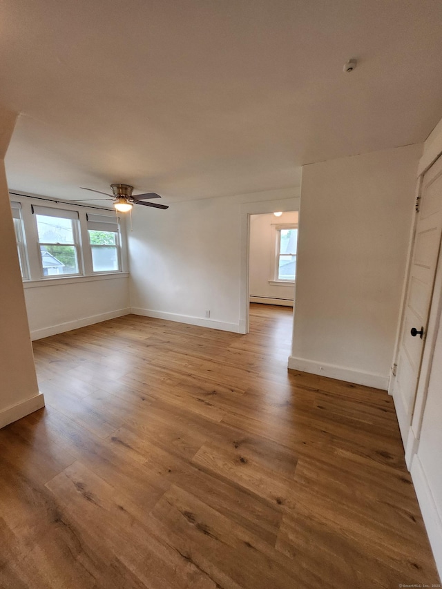 spare room with a baseboard radiator, a healthy amount of sunlight, and wood finished floors