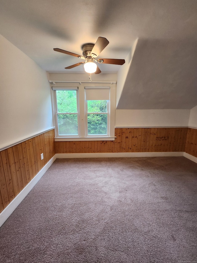 bonus room with wood walls, baseboards, ceiling fan, and carpet floors