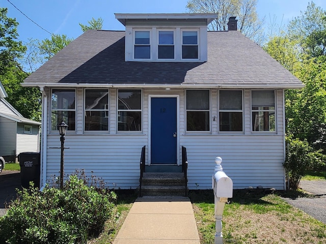 bungalow-style house featuring roof with shingles, entry steps, and a chimney