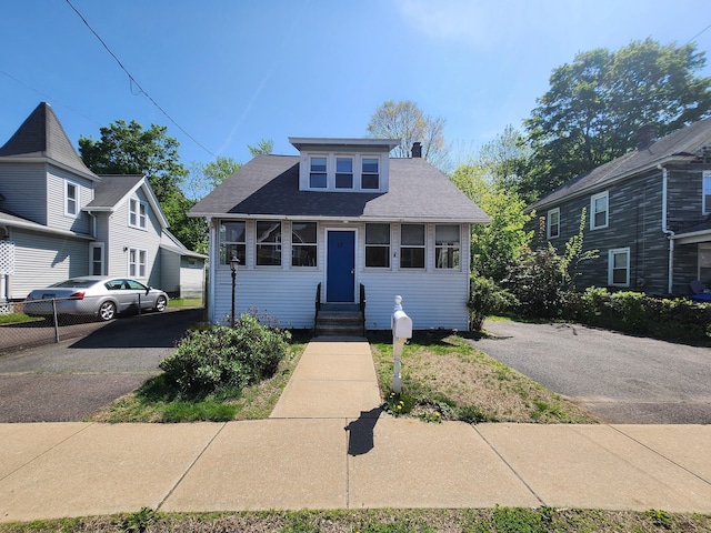 bungalow-style house with entry steps, aphalt driveway, and a shingled roof