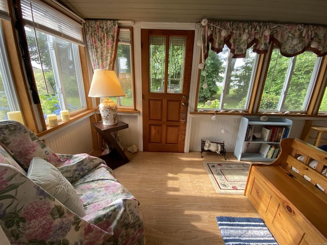 sunroom with wooden walls and wood finished floors