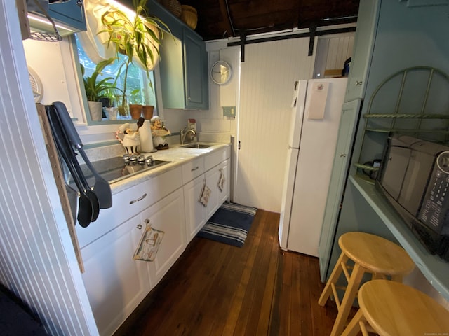 kitchen with freestanding refrigerator, dark wood-style flooring, a sink, black electric stovetop, and light countertops