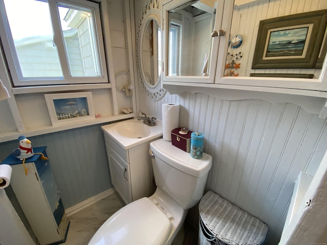 bathroom featuring toilet, wooden walls, and vanity