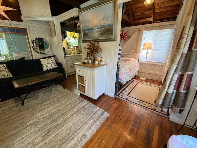 living room with wooden walls, beamed ceiling, and dark wood-style floors