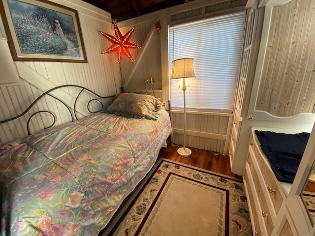 bedroom with wood walls and wood finished floors