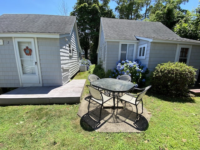 exterior space featuring outdoor dining area, a wooden deck, and an outbuilding