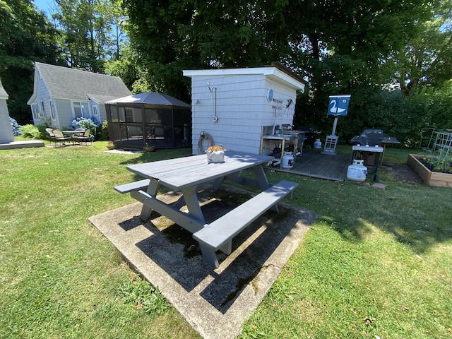 view of yard featuring outdoor dining space, an outdoor structure, a storage unit, and a wooden deck
