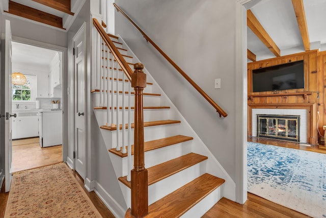staircase featuring wood finished floors and a glass covered fireplace