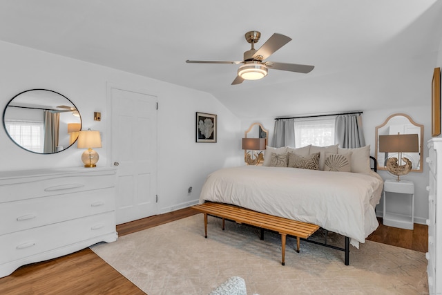 bedroom with baseboards, light wood-style flooring, lofted ceiling, and ceiling fan