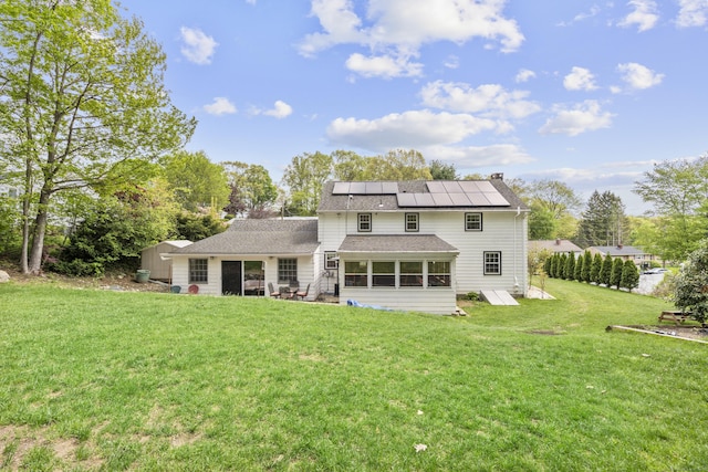 back of property featuring a sunroom, solar panels, a yard, a chimney, and a shingled roof