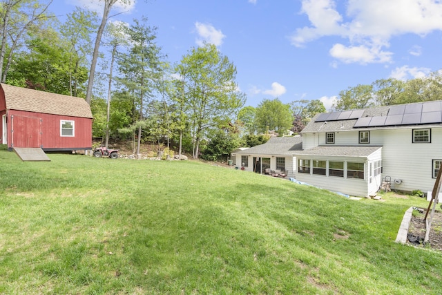 view of grassy yard with an outbuilding, a sunroom, and a storage shed
