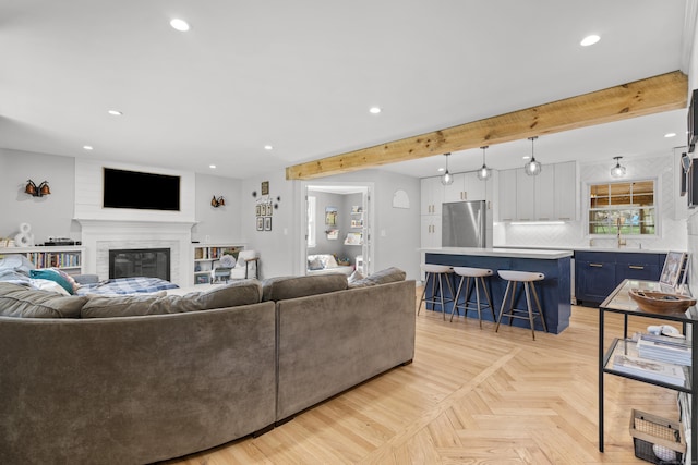 living room featuring recessed lighting, beam ceiling, and a glass covered fireplace
