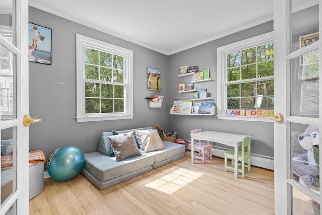 recreation room featuring wood finished floors, plenty of natural light, and crown molding