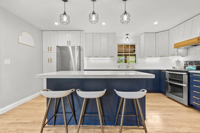 kitchen with appliances with stainless steel finishes, blue cabinetry, a kitchen breakfast bar, a center island, and recessed lighting