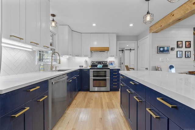 kitchen featuring blue cabinetry, appliances with stainless steel finishes, a sink, white cabinets, and light wood-style floors
