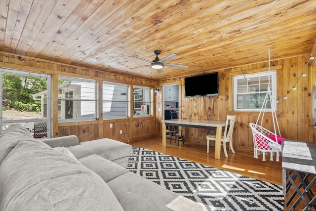 living room featuring wood ceiling, wooden walls, wood finished floors, and a ceiling fan