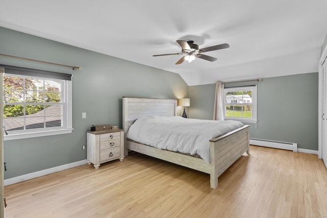 bedroom with baseboard heating, light wood-style flooring, baseboards, and a ceiling fan