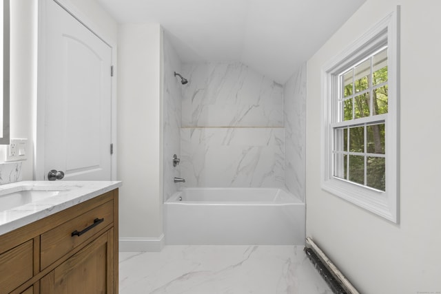 bathroom featuring marble tiled flooring, vanity, washtub / shower combination, baseboards, and lofted ceiling