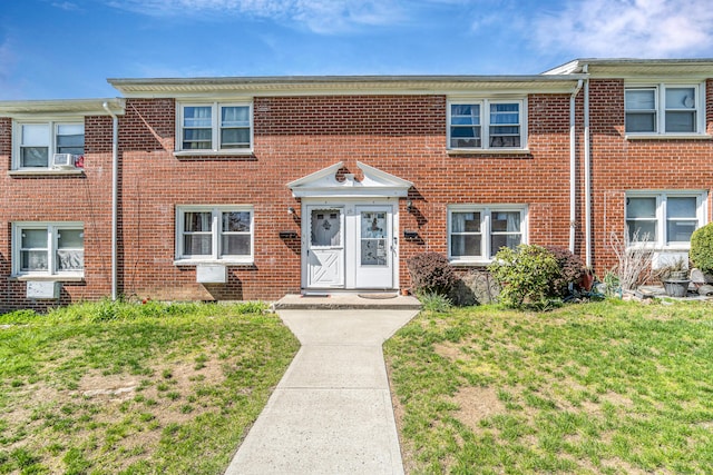 multi unit property with a front yard and brick siding