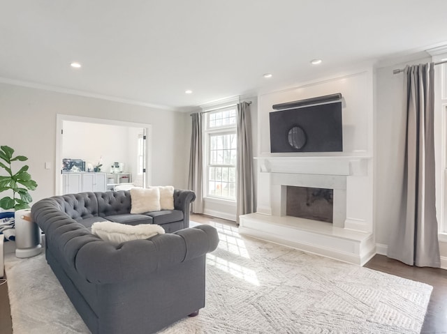 living room with recessed lighting, a glass covered fireplace, and ornamental molding