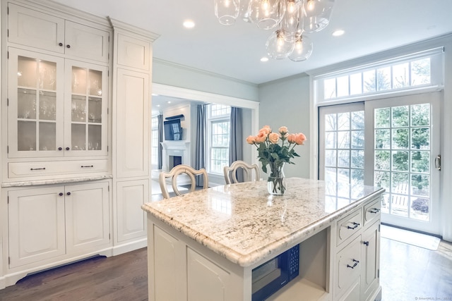 kitchen featuring glass insert cabinets, recessed lighting, white cabinetry, a chandelier, and light stone counters