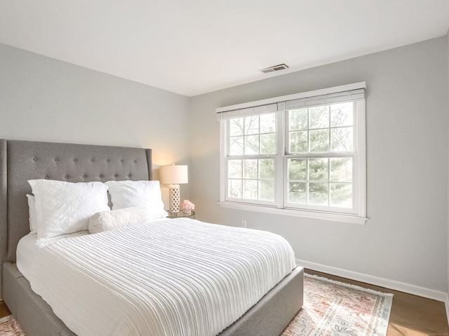 bedroom featuring baseboards, visible vents, and wood finished floors