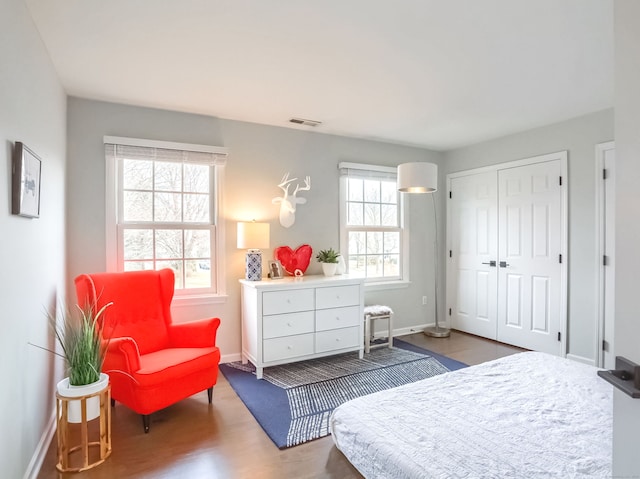 bedroom with baseboards, a closet, wood finished floors, and visible vents