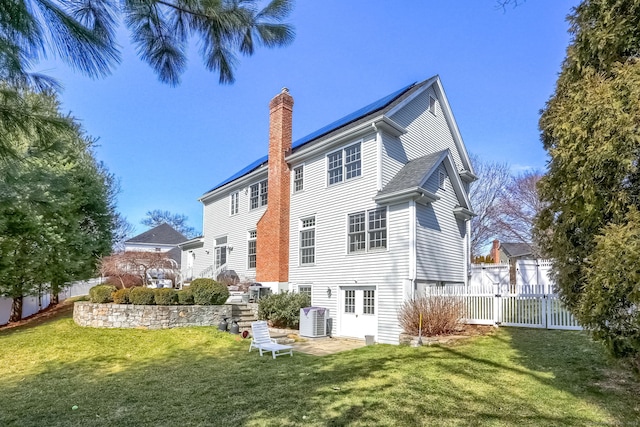 back of house with fence, cooling unit, a chimney, a gate, and a yard