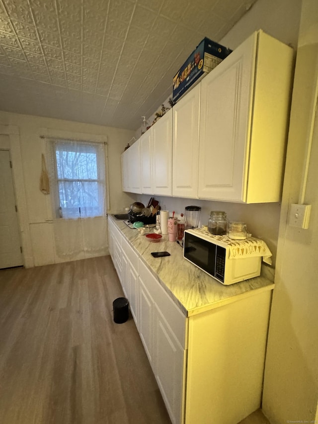 kitchen with light countertops, white cabinetry, and light wood-type flooring