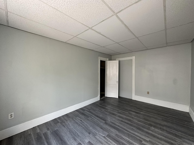 unfurnished room featuring baseboards, dark wood-style floors, and a drop ceiling