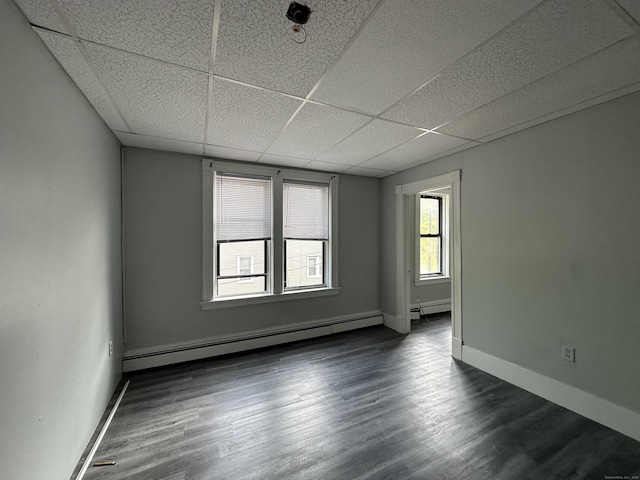 spare room with baseboards, dark wood finished floors, a paneled ceiling, and a baseboard radiator