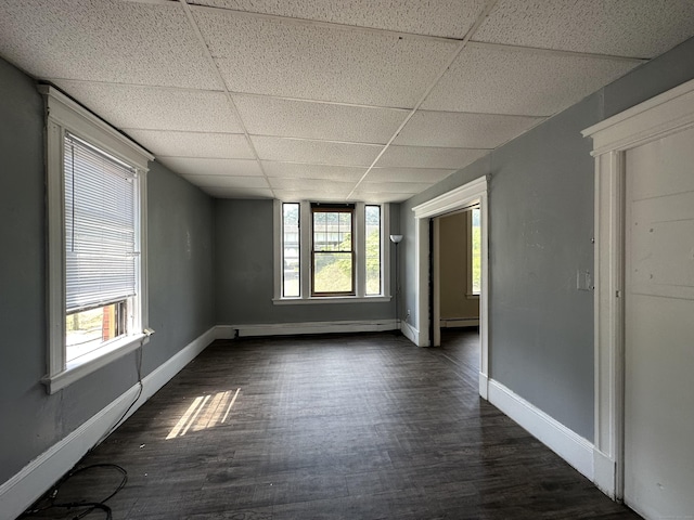 empty room with baseboards, a baseboard radiator, dark wood-style floors, and a paneled ceiling