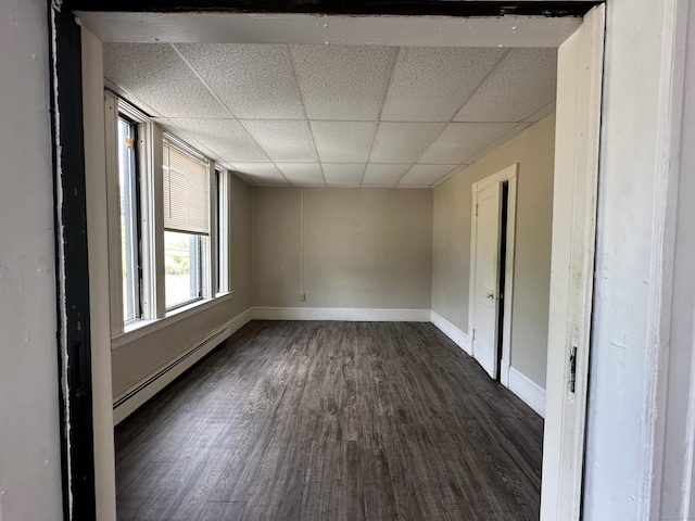 spare room featuring dark wood-style flooring, baseboards, a baseboard heating unit, and a paneled ceiling