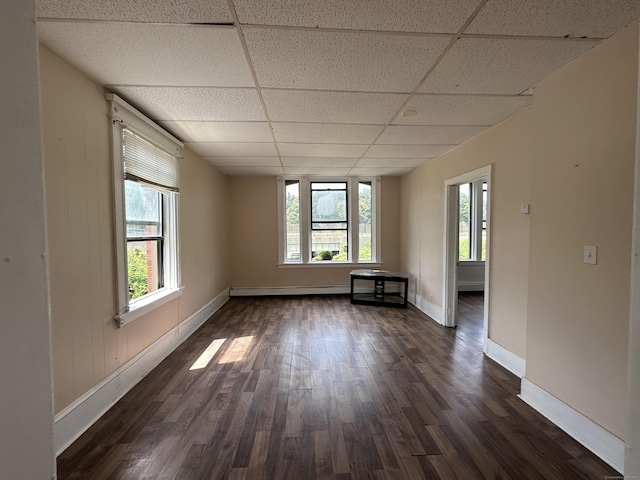 empty room with dark wood-style flooring, baseboards, a paneled ceiling, and a baseboard radiator