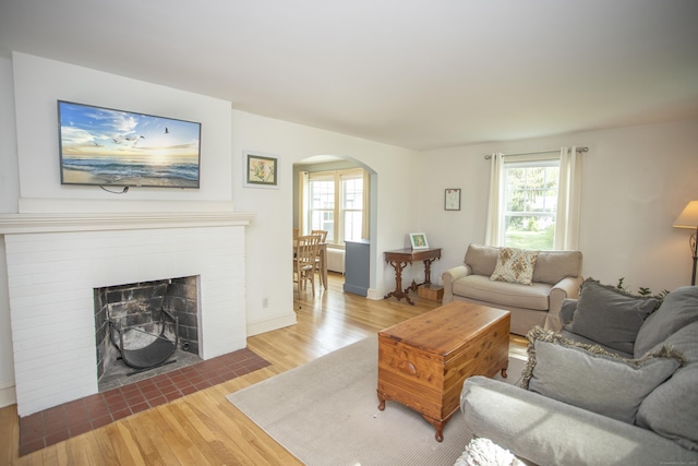 62 Lynde St, Old Saybrook, CT 06475 - living area featuring arched walkways, wood finished floors, a brick fireplace, and baseboards