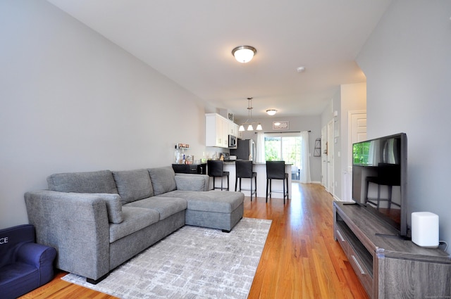 living room featuring light wood finished floors and a chandelier
