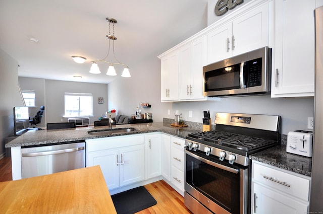 kitchen featuring stainless steel appliances, a sink, white cabinets, and light wood-type flooring