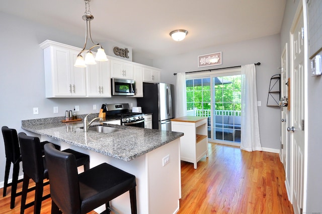 kitchen featuring appliances with stainless steel finishes, a kitchen island, white cabinetry, and light wood finished floors