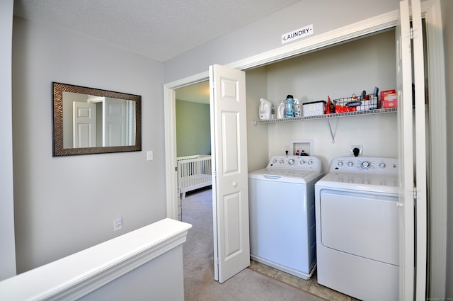 clothes washing area with washer and dryer, light carpet, and a textured ceiling