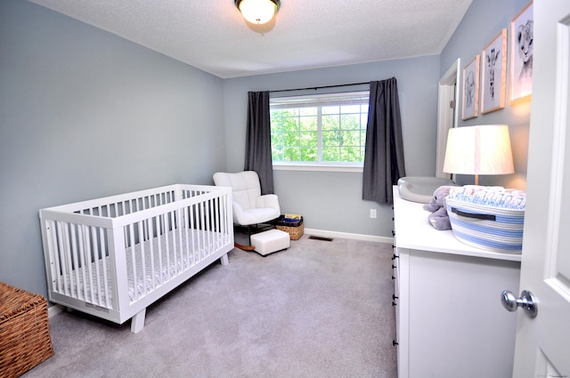bedroom featuring carpet floors, a textured ceiling, a crib, and baseboards
