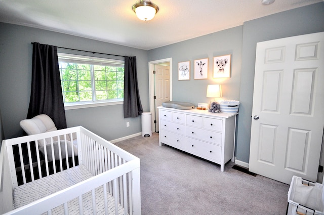 carpeted bedroom with a crib and baseboards