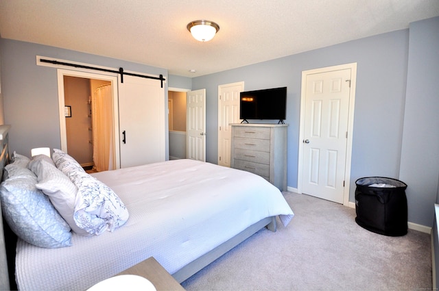 bedroom featuring a barn door, light colored carpet, and baseboards