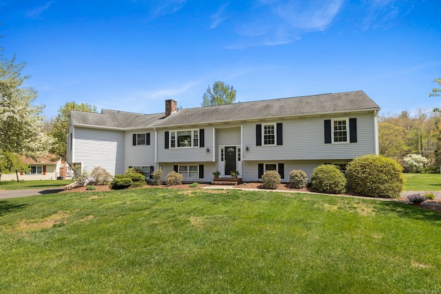 bi-level home with a chimney, a front yard, and entry steps