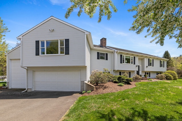 split foyer home with a garage, a front yard, a chimney, and driveway